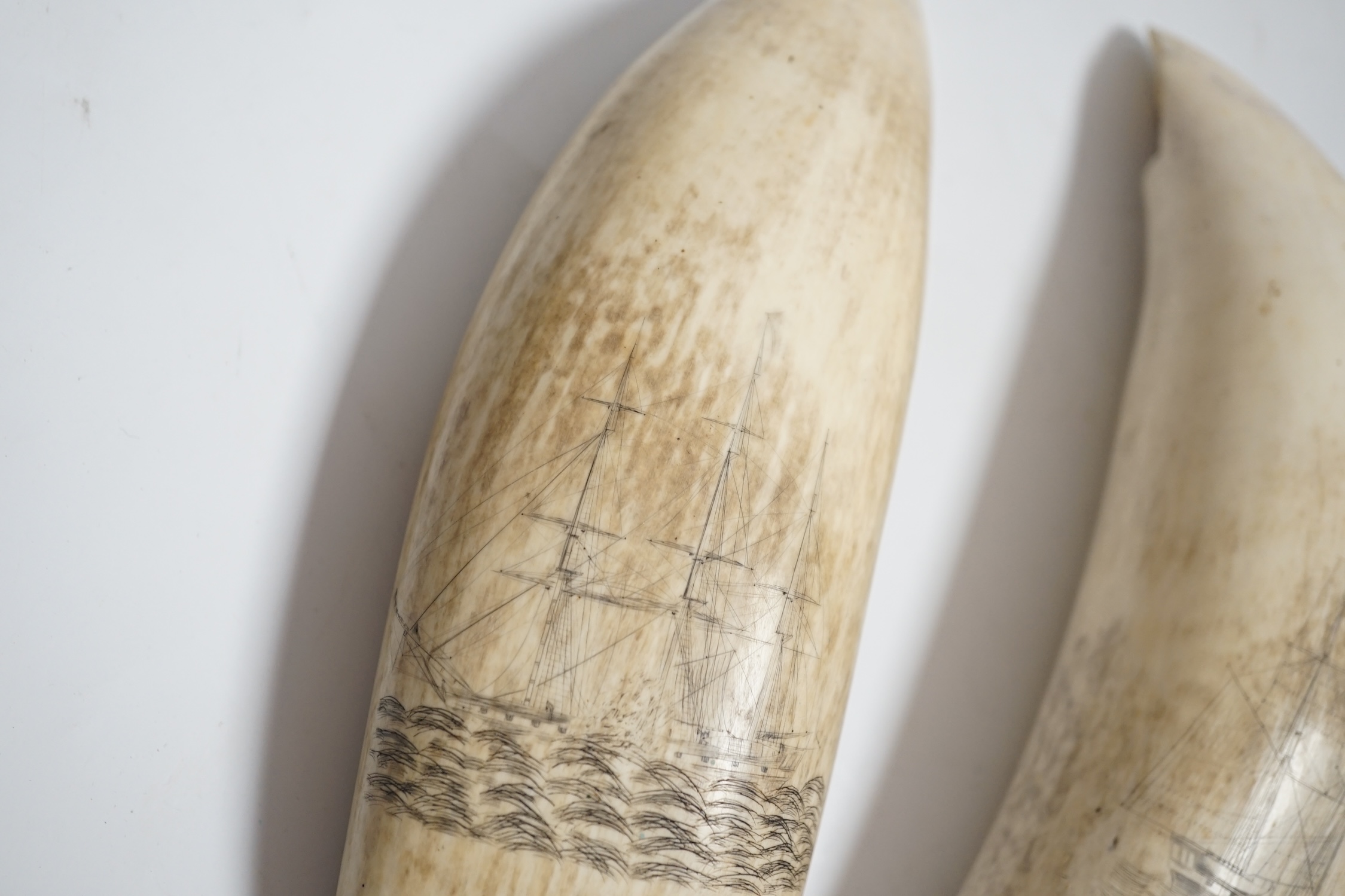 Two 19th century scrimshaw sperm whale teeth, each incised with a ship, 20cm in length